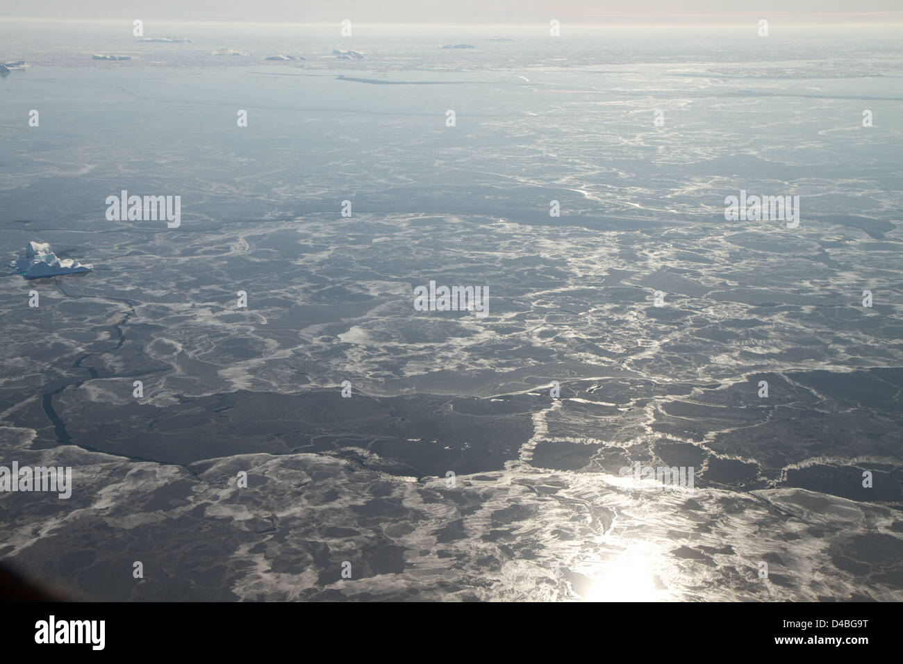 Les images satellites de la NASA capturent l'évolution du paysage arctique, mettant en valeur de la glace de mer vitreuse et un iceberg, mettant l'accent sur les changements environnementaux en cours dans les régions polaires. Banque D'Images