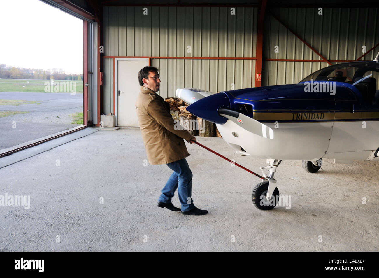 Un pilote tirant son avion léger hors de son hangar Banque D'Images