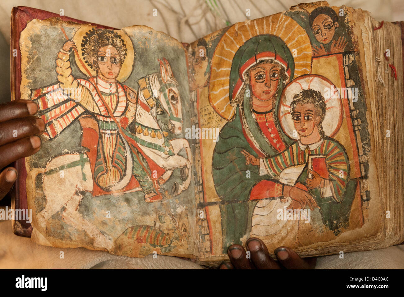 Un prêtre orthodoxe éthiopienne tient un livre montrant des images distinctes de St George et la vierge Marie avec le jeune Jésus Christ Banque D'Images