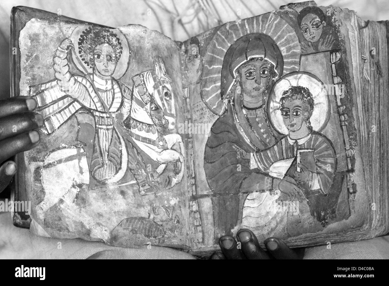Un prêtre orthodoxe éthiopienne tient un livre montrant des images distinctes de St George et la vierge Marie avec le jeune Jésus Christ Banque D'Images