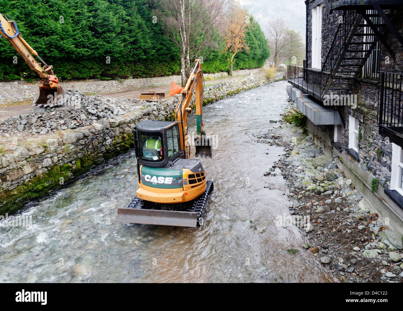 Un type JCB digger travaillant dans une rivière de Penrith, le Lake District, en Angleterre Banque D'Images