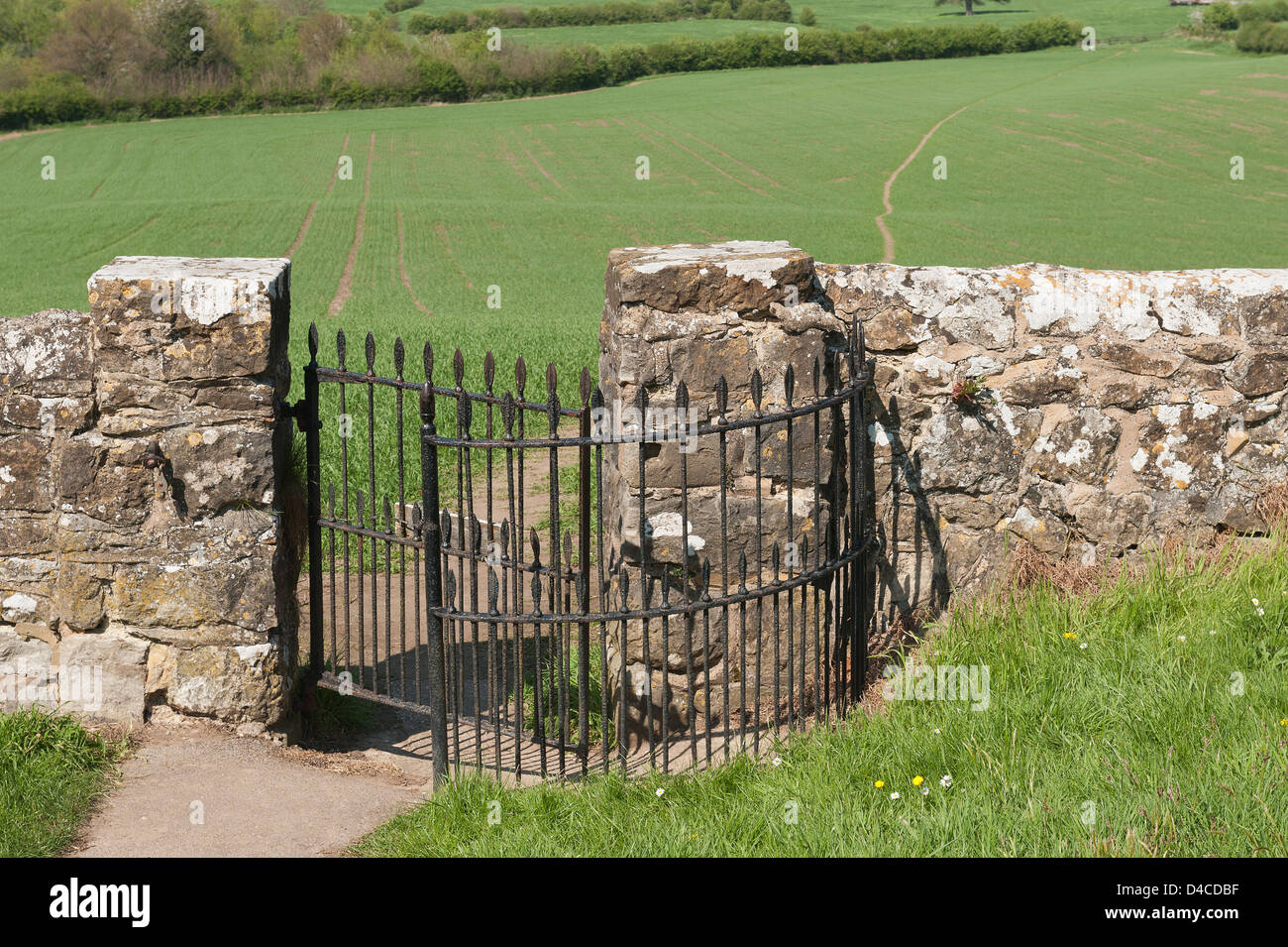 La porte en fer forgé s'embrasser et kent ragstone mur menant vers l'ensemble de sentier domaine de la campagne de récolte de blé ceinture verte Banque D'Images