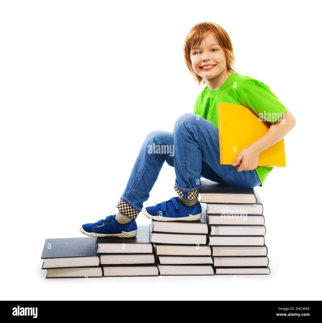 Happy woman 9 ans garçon en chemise verte debout sur les escaliers faits de pile de livres holding yellow livre relié, isolated on white Banque D'Images
