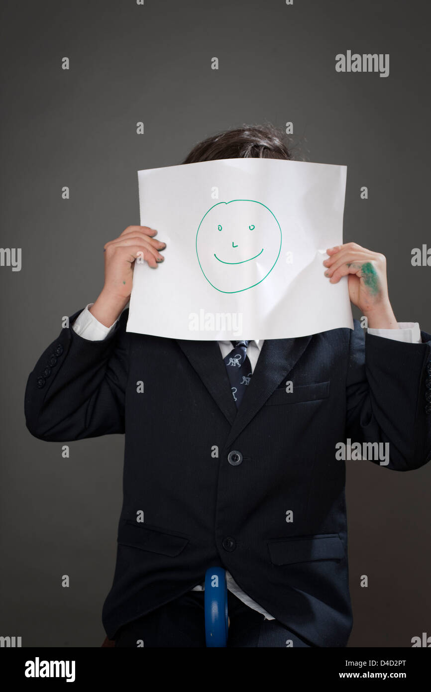 Boy covering face avec dessin de visage heureux Banque D'Images