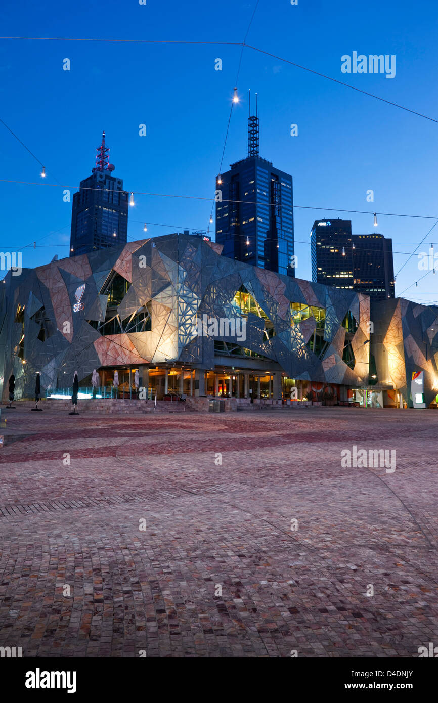 Federation Square allumé au crépuscule avec ville en arrière-plan. Melbourne, Victoria, Australie Banque D'Images