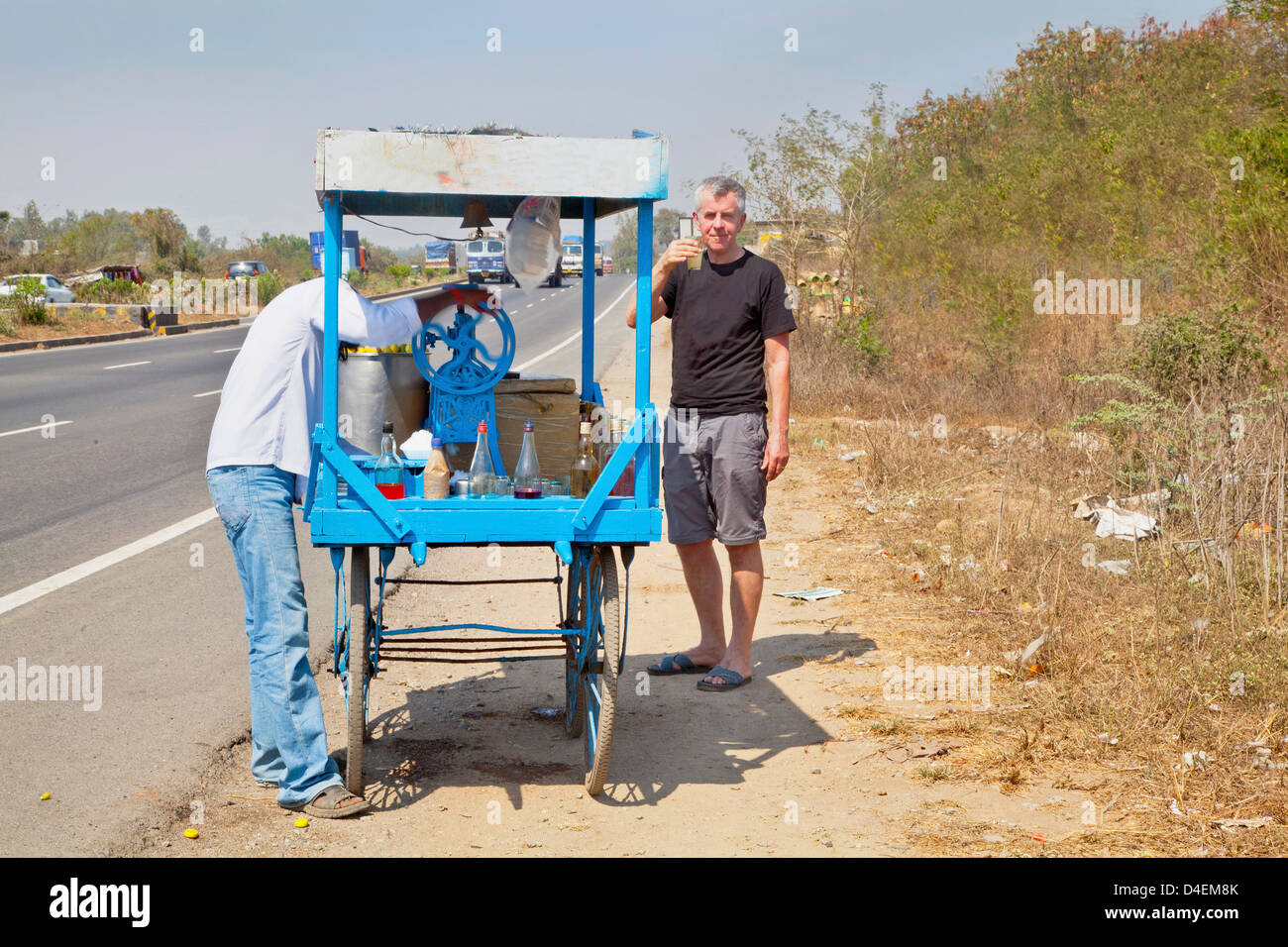 L'homme achète une boisson rafraîchissante par Affaires indiennes route et assouvit la soif de vendeur de rue Banque D'Images