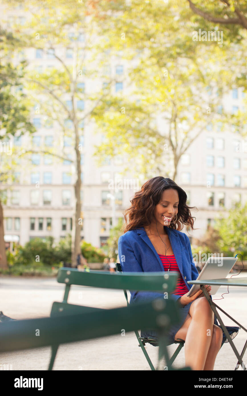 Woman using digital tablet at sidewalk cafe Banque D'Images
