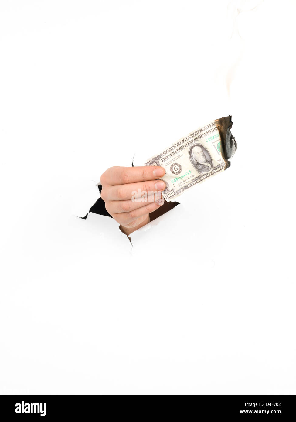 Close-up of man's hand holding a burning dollar bill à travers une déchirure de papier blanc, isolé Banque D'Images
