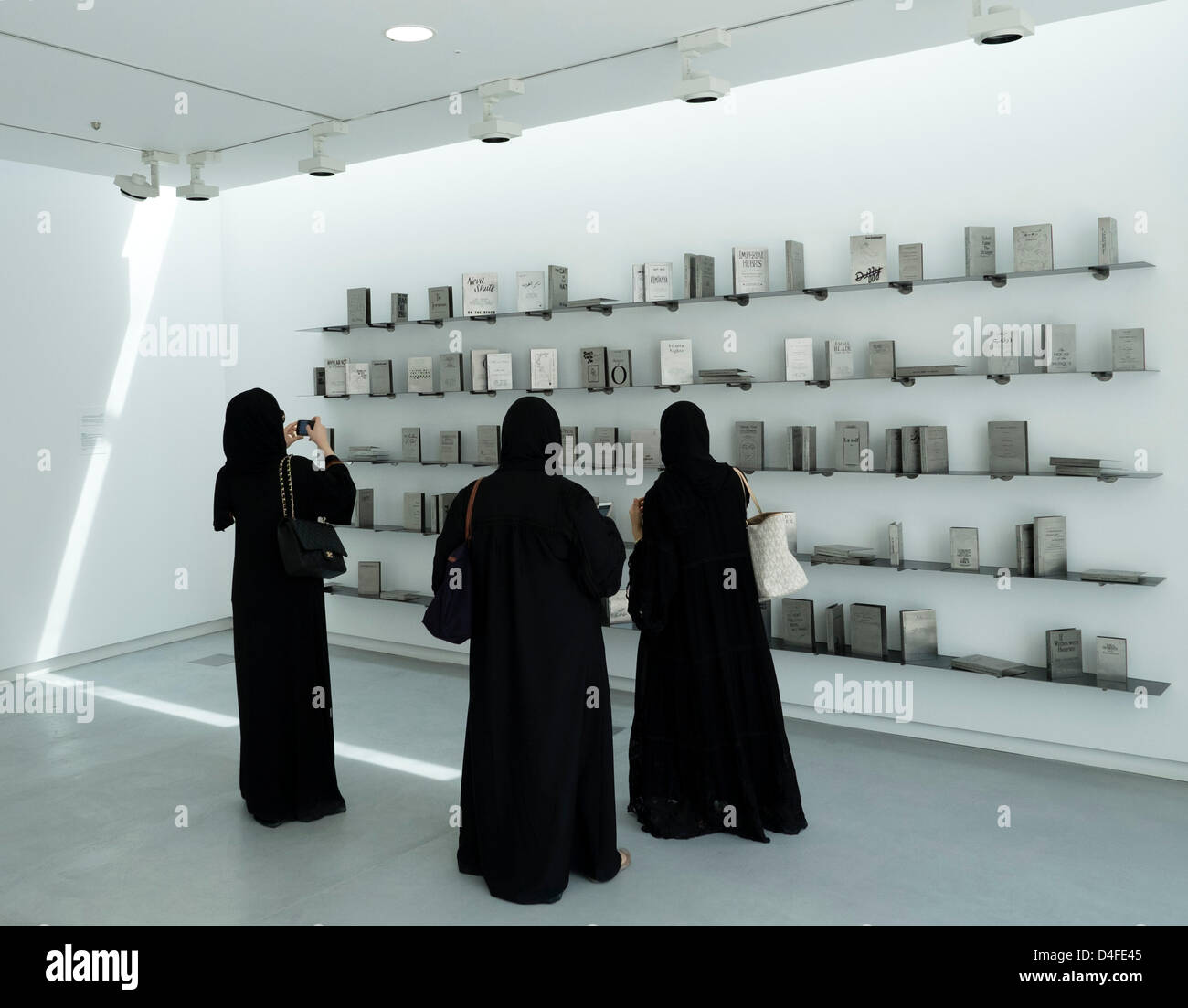 Les visiteurs qui cherchent à la pièce par Shilpa Gupta intitulé quelqu'un d'autre une collection de livres en acier inoxydable gravé le jour de l'ouverture de la 11ème Biennale de Sharjah Art Festival à Emirats Arabes Unis Banque D'Images