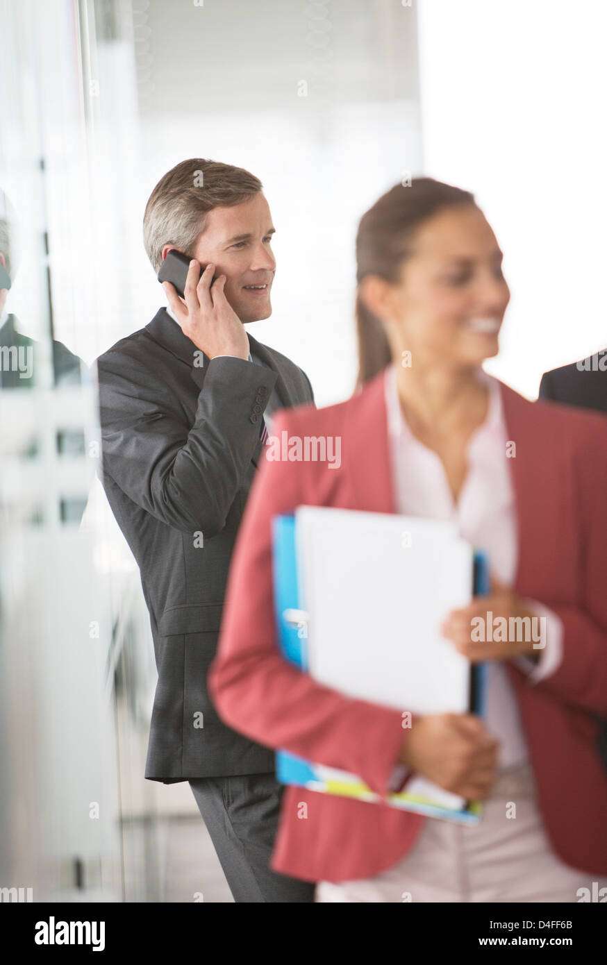Businessman talking on cell phone in office corridor Banque D'Images