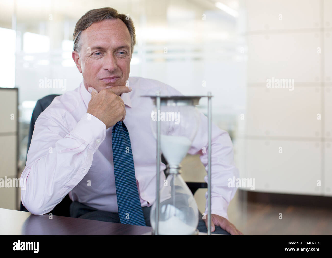Businessman watching hourglass in office Banque D'Images