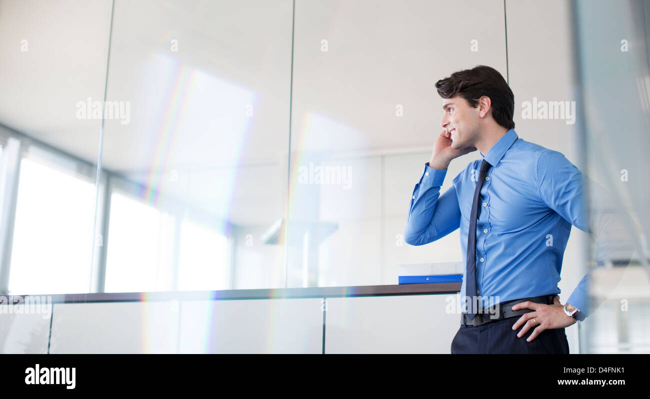 Businessman talking on cell phone in office Banque D'Images