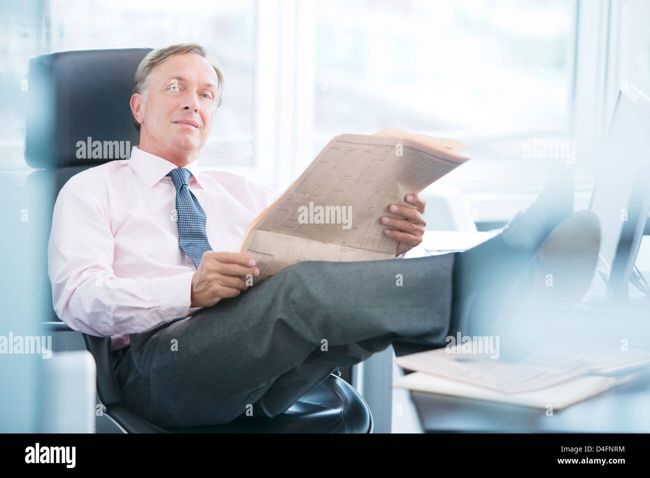 Businessman reading newspaper in office Banque D'Images