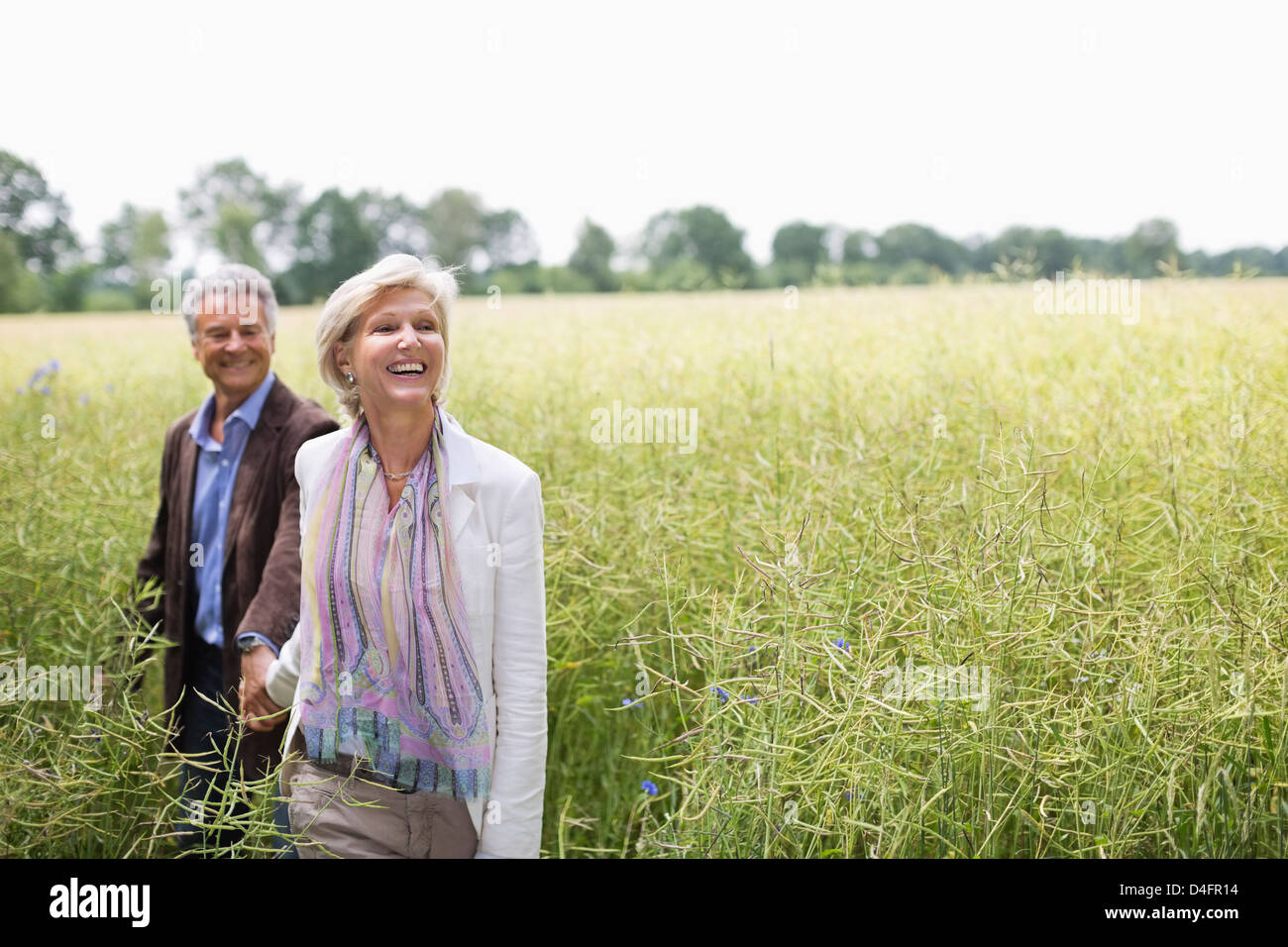 Couple walking in field of tall grass Banque D'Images