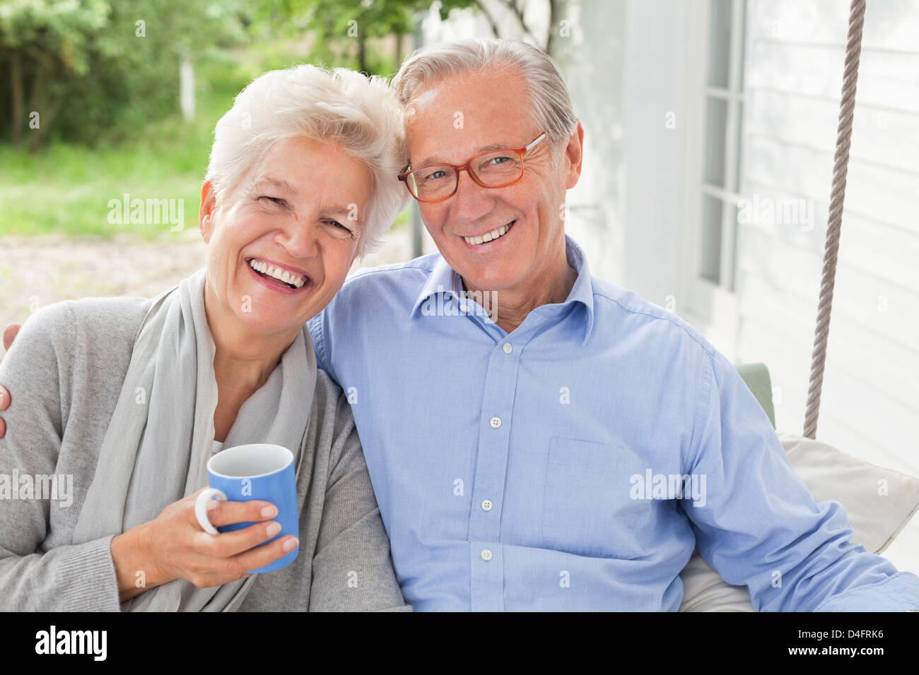 Smiling couple sitting on porch swing Banque D'Images