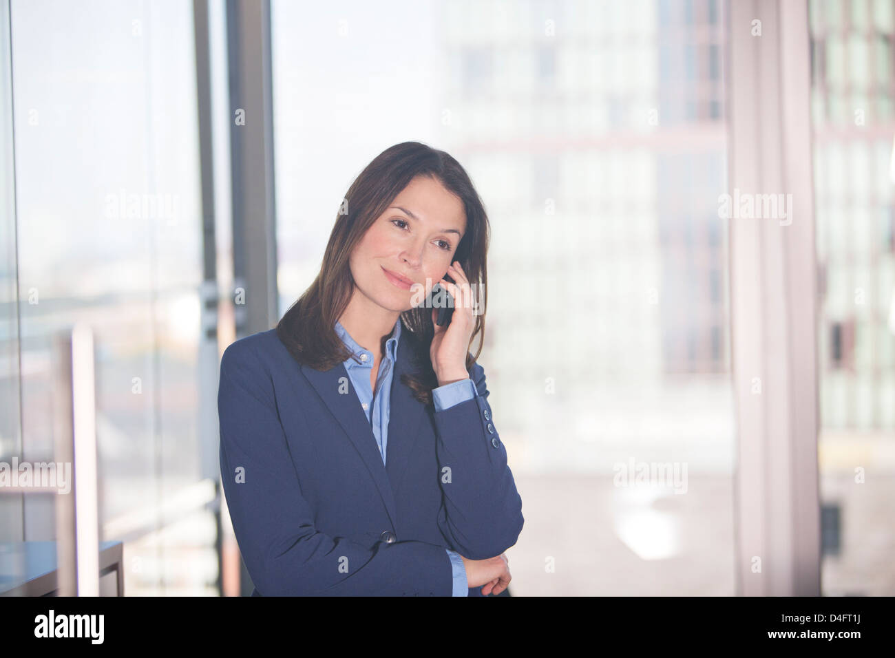 Businesswoman talking on cell phone in office Banque D'Images