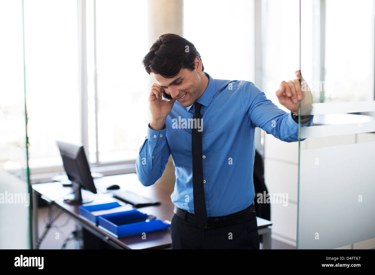 Businessman talking on cell phone in office Banque D'Images