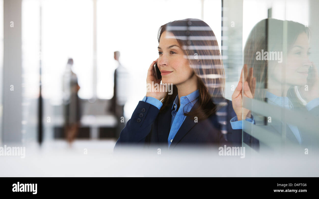 Businesswoman talking on cell phone in office Banque D'Images