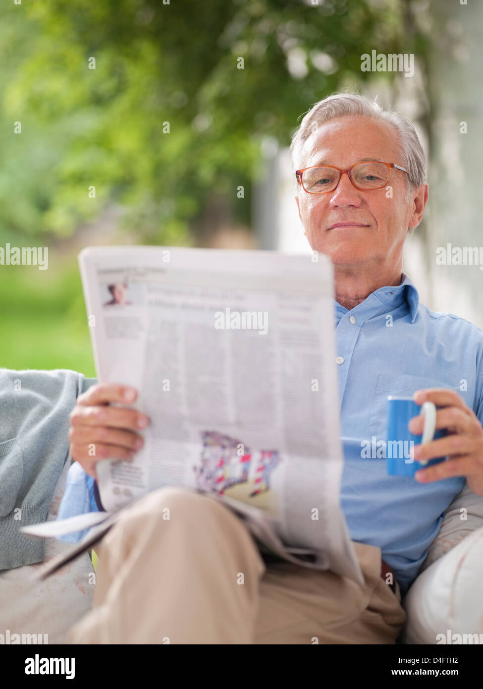 Man reading newspaper in porch swing Banque D'Images