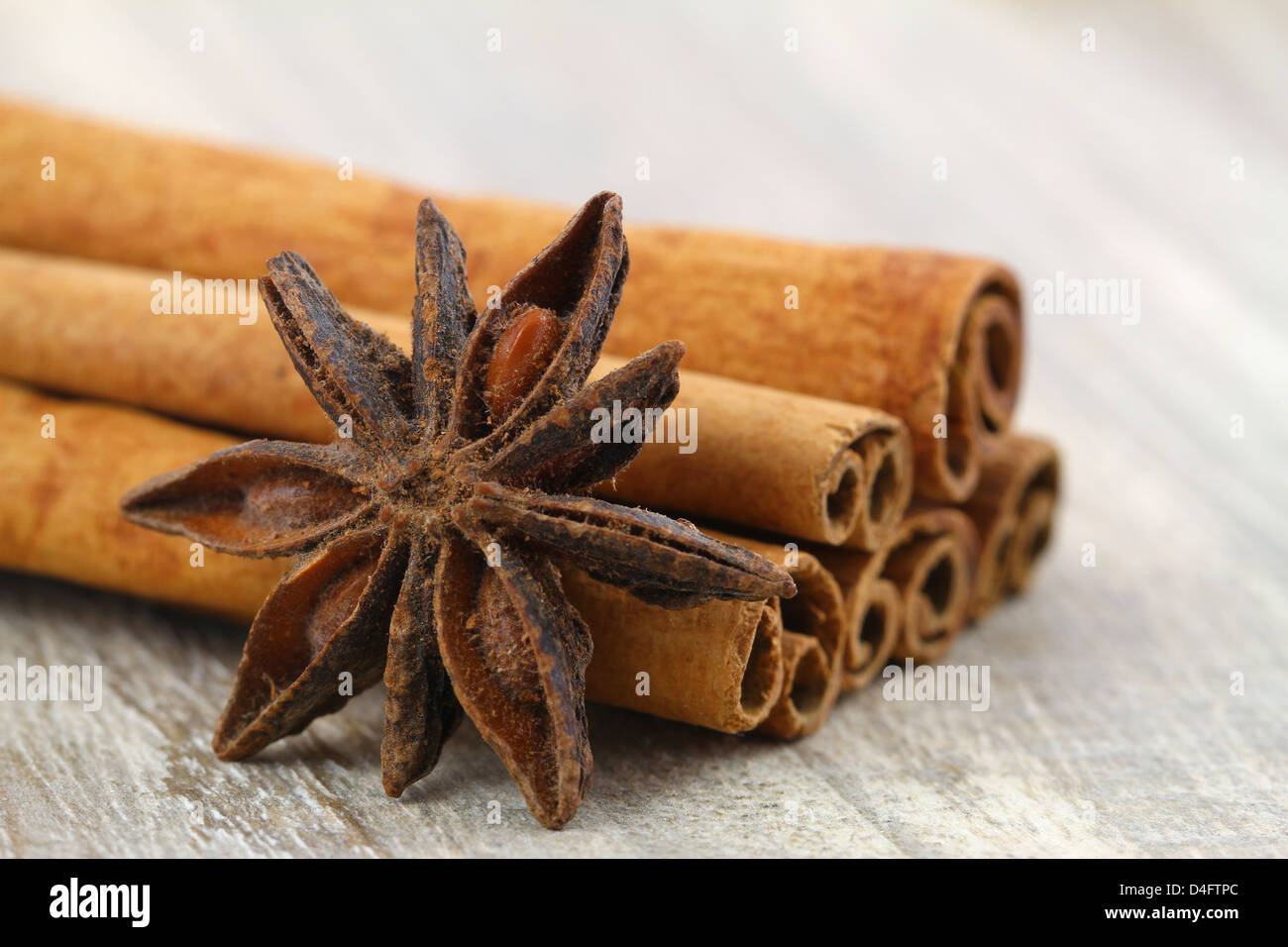 L'anis étoilé appuyé contre des bâtons de cannelle sur fond de bois Banque D'Images