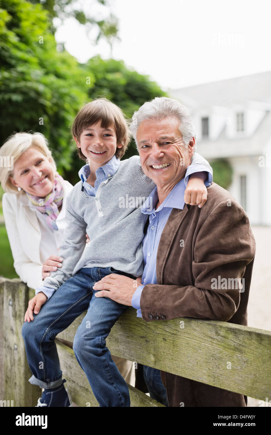 Petit-fils et couple smiling par clôture en bois Banque D'Images