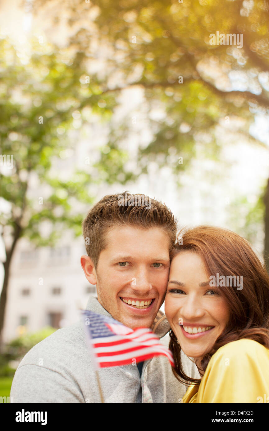 Couple waving American flag in urban park Banque D'Images