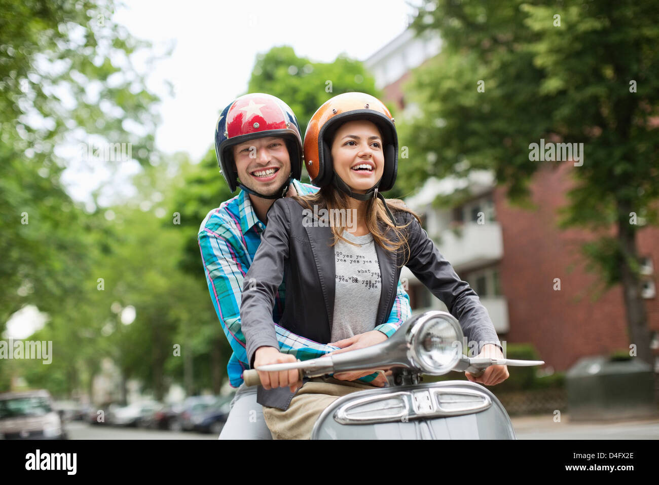 Couple riding scooter together on city street Banque D'Images