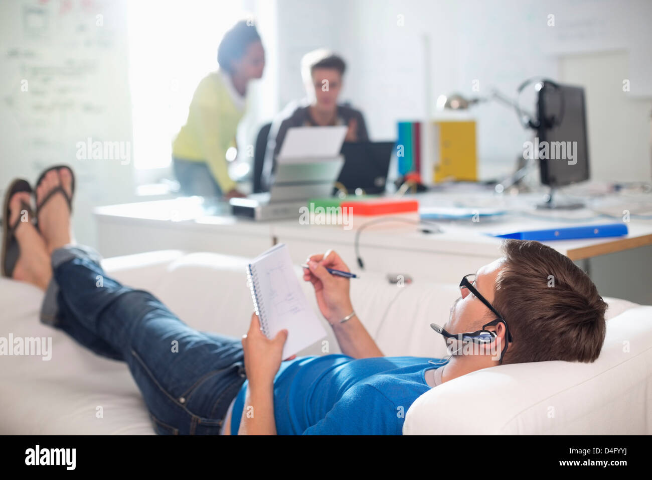 Businessman taking notes on sofa in office Banque D'Images
