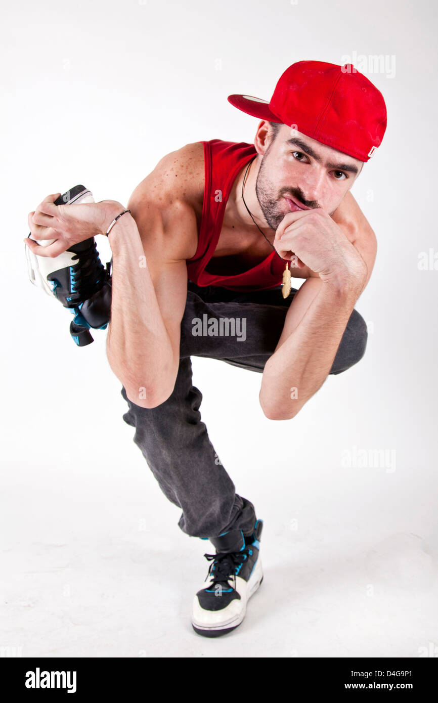 Jeune homme assis avec sérieux bboy bouchon rouge sur un pied Banque D'Images