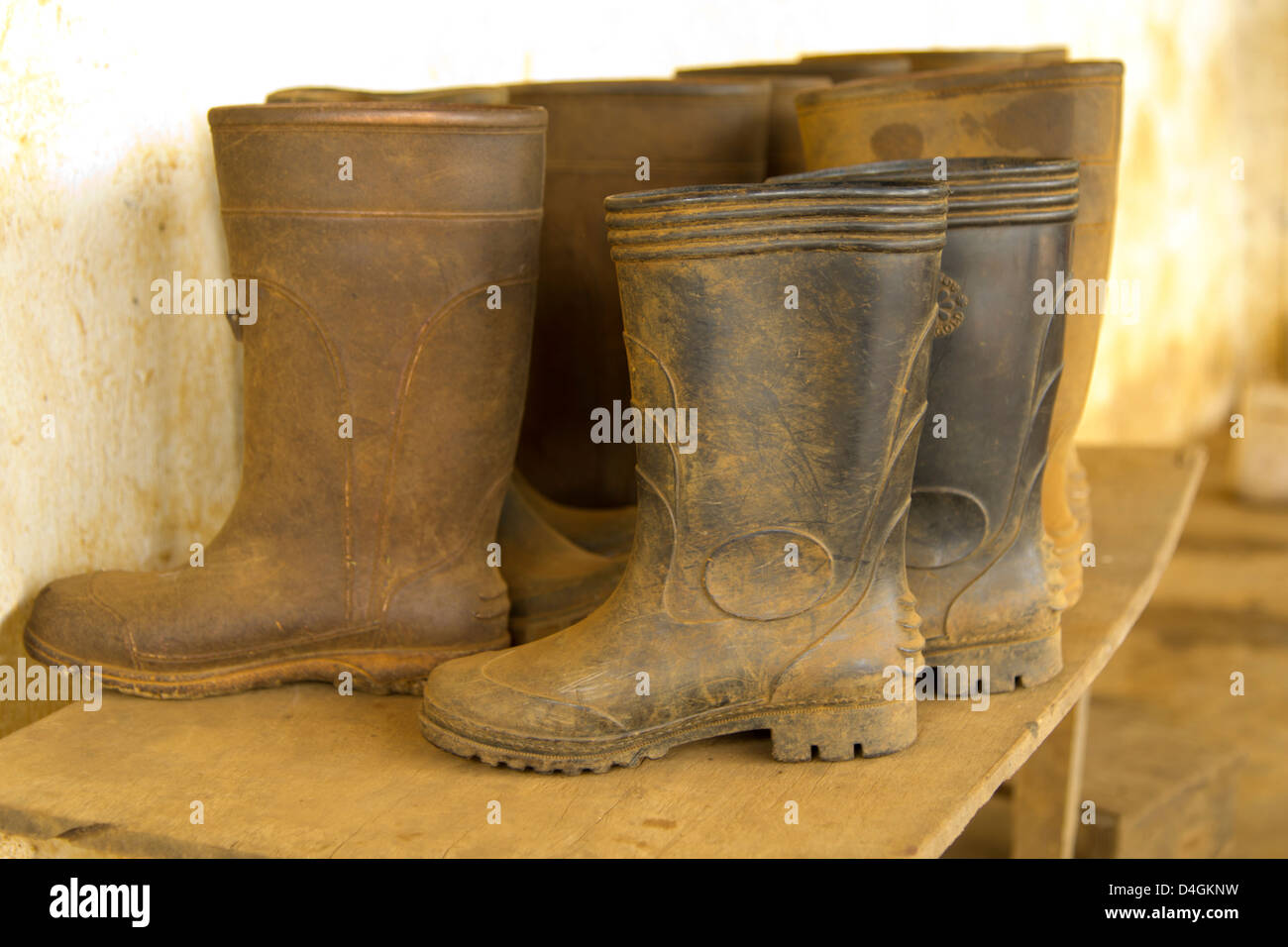 Bottes en caoutchouc boueux est assis sur une table en bois Banque D'Images