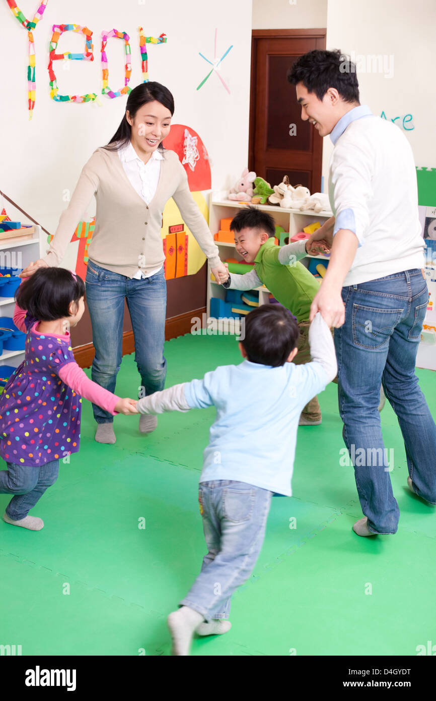 Joyeux Enfants de la maternelle de jouer aux jeux avec les enseignants Banque D'Images