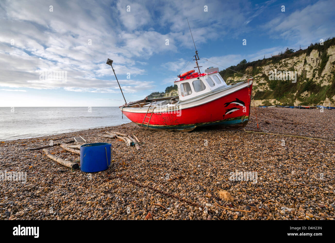 Bateau de pêche rouge sur la plage de la bière sur la côte jurassique du Devon Banque D'Images