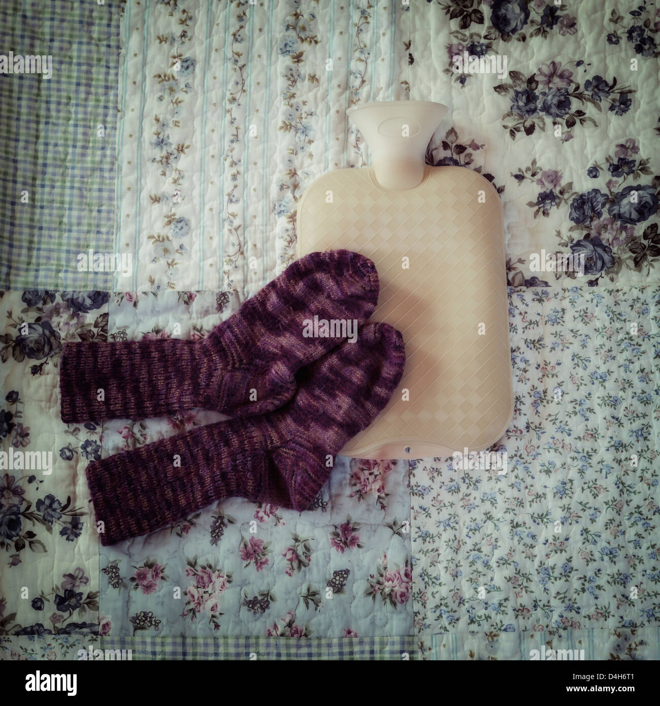 Bouteille à eau chaude avec des chaussettes tricotées main sur un lit vintage Banque D'Images