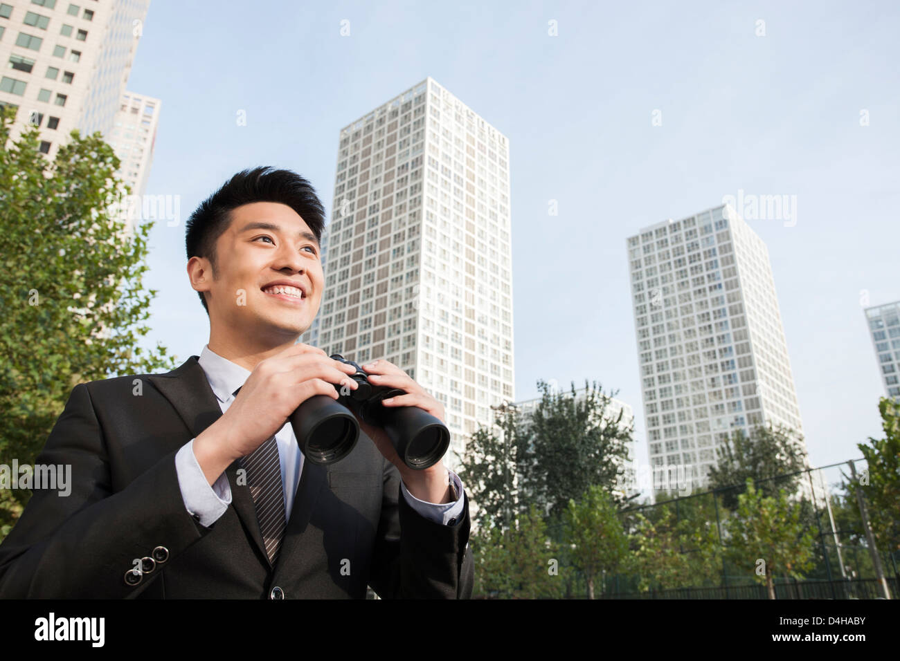 Cheerful young businessman avec des jumelles à la vue au centre-ville en Banque D'Images
