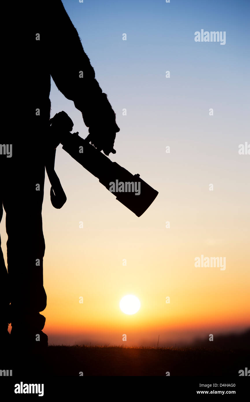La photographe d'un appareil photo avec un objectif grand au lever du soleil. Silhouette Banque D'Images