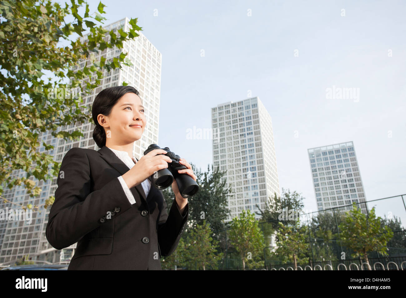 Young businesswoman with binoculars looking at view dans downtown district Banque D'Images