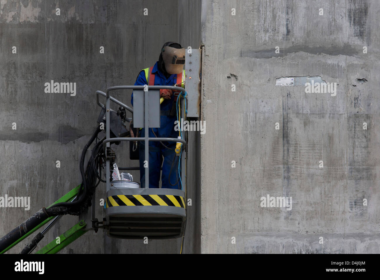 Un soudeur travaille en hauteur depuis le sol à partir de la sécurité d'une plate-forme hydraulique sur le côté d'un ascenseur en construction sur l'arbre d'un vaste projet de développement sur mur de Londres dans la ville de Londres, le quartier financier de la capitale, également connu sous le nom de Square Mile. Avec la visière de son casque éclairé par la lueur de sa torche de l'acétylène, l'homme se penche vers le détail de cette close-up Contact Offres d'emplois. Soudure oxy-combustible (communément appelé soudage oxyacétylénique, soudure oxy, ou le soudage au gaz aux États-Unis) et de l'oxy-coupage de carburant sont des processus qui utilisent les gaz combustibles et l'oxygène pour souder et couper des métaux, respectivement. Banque D'Images