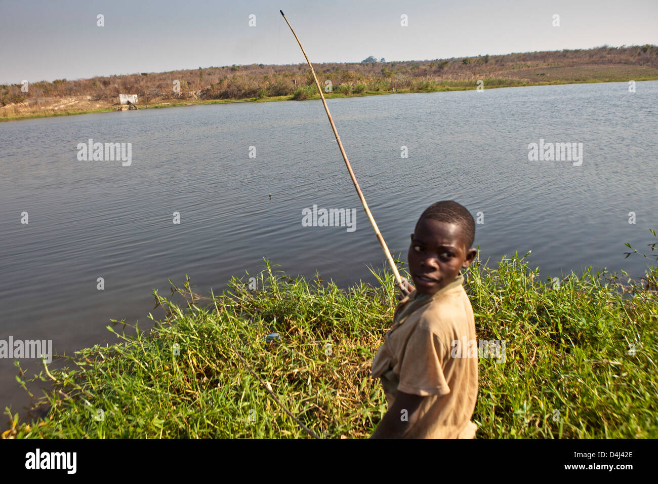 African boy de la pêche sur le lac de Kubatsirana Farm géré par un organisme de bienfaisance qui aident à fournir de la nourriture et le travail, au Mozambique. Banque D'Images
