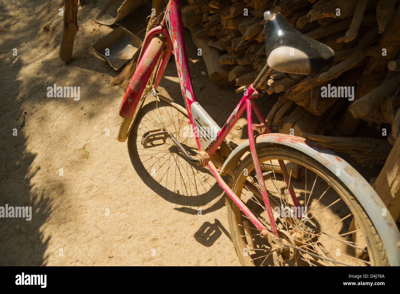 Un vélo rouge et recouverts de poussière dans le soleil ; l'ombre de la roue avant et de la pédale gauche Banque D'Images