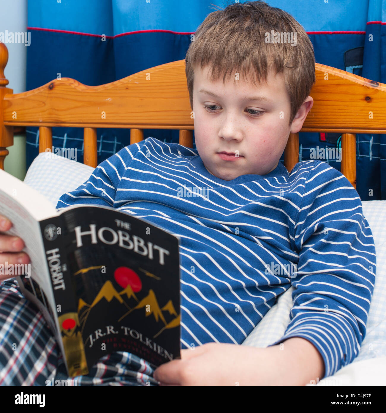Un garçon de neuf ans, la lecture du livre de Hobbit dans sa chambre à coucher Banque D'Images
