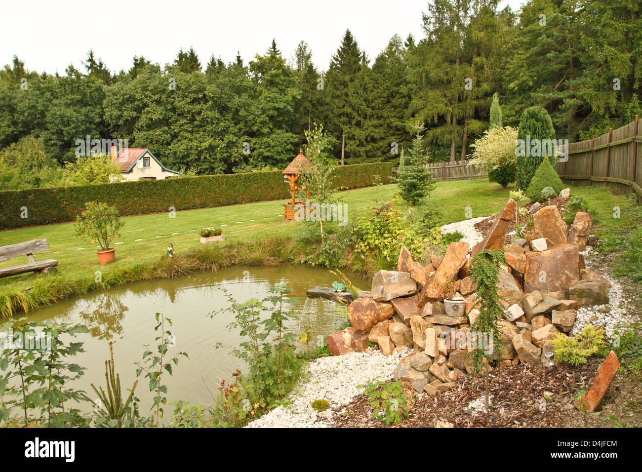Jardin avec étang, pierres et bois de chauffage Banque D'Images