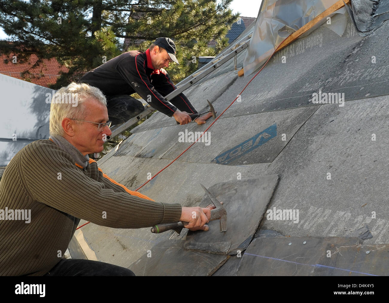 Slaters Werner Uhlmann (L) et Udo Dabek du pavillon carreleur company Hartenstein commencer la réparation de la toiture de l'église dans Limbach-Oerfrohna, Allemagne, 31 mars 2009. A 23 ans, conducteur d'un Skoda manqué un tour dans la nuit du 25 janvier 2009 et s'est écrasé sur le toit de l'église ?s. Son unique stunt a causé une sensation dans le monde entier. Selon l'opinion de l'expert, l'homme avait accéléré à 13 Banque D'Images