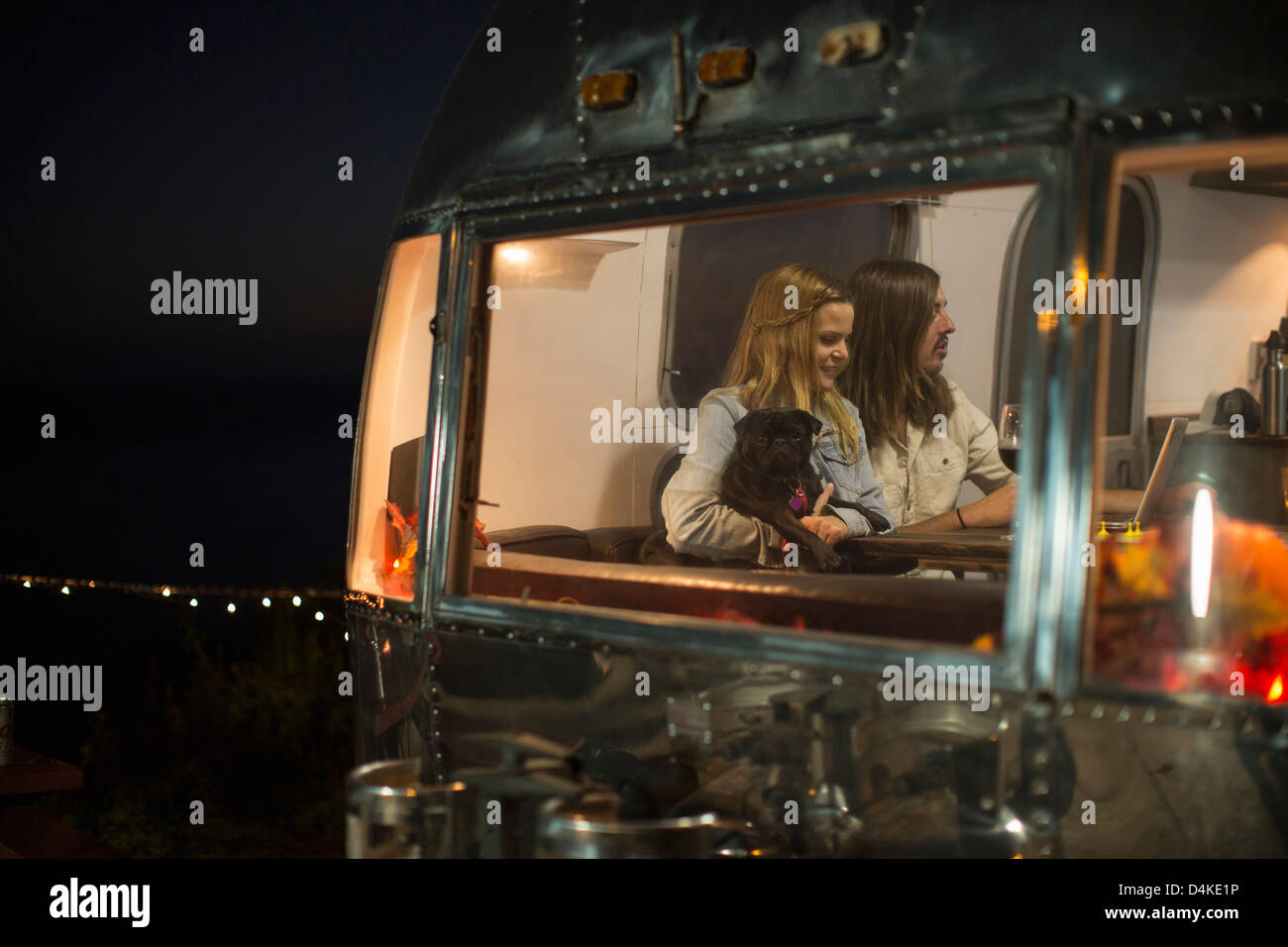 Couple relaxing with dog in trailer Banque D'Images