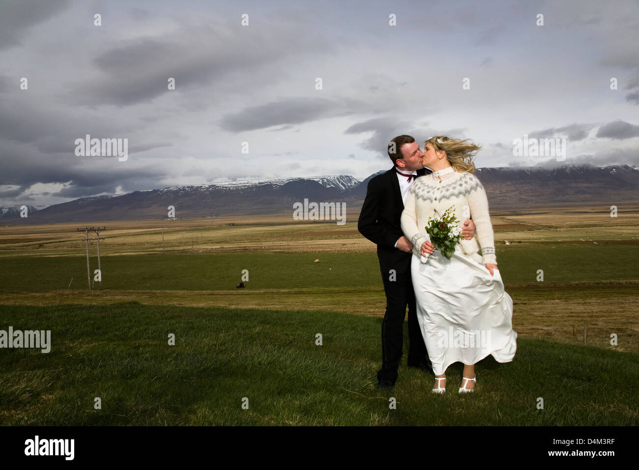 Newlywed couple kissing in rural field Banque D'Images