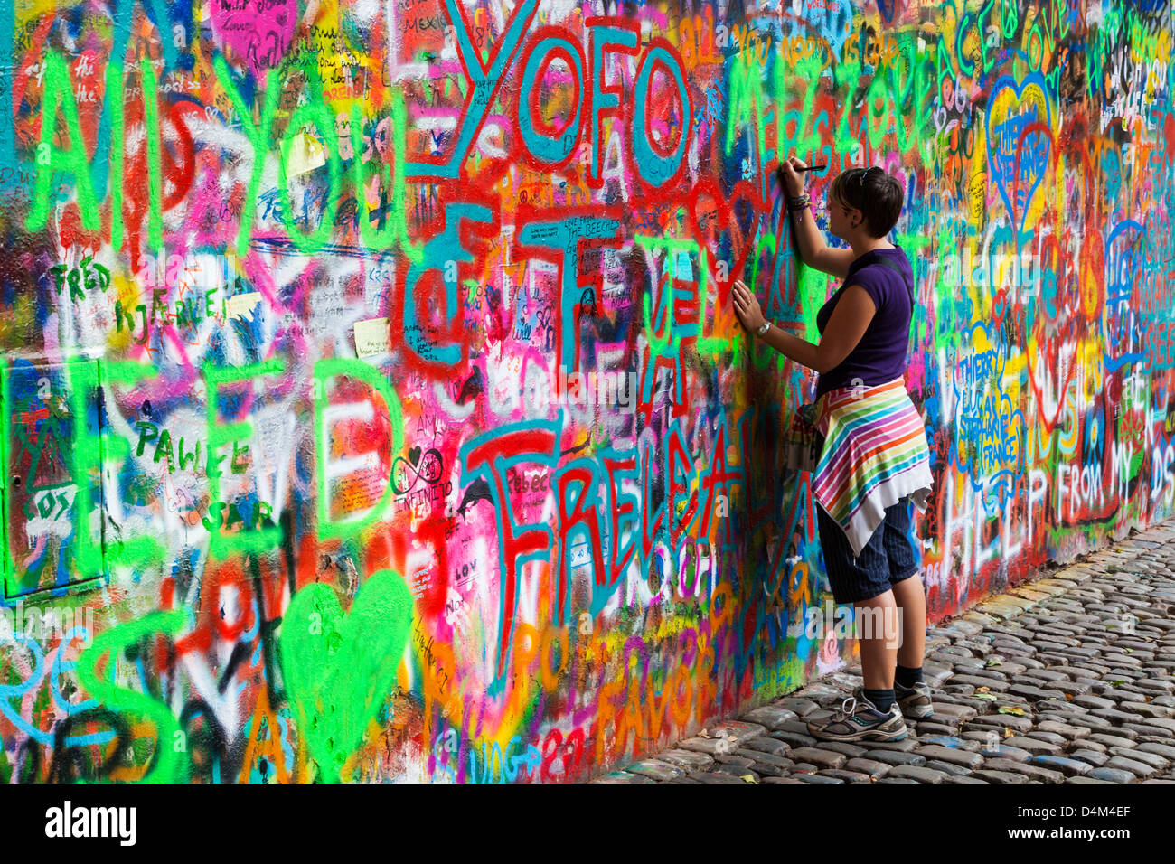 Une jeune fille touristiques ajoute à la graffiti Wall John Lennon à Prague, Prague, République tchèque,Česká Republika,Europe Banque D'Images