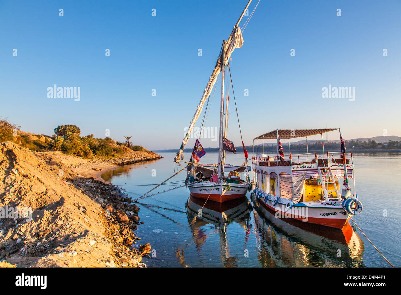 1900 tourisme et l'appui bateau amarré le long de la rive est du Nil près d'Assouan au lever du soleil. Banque D'Images
