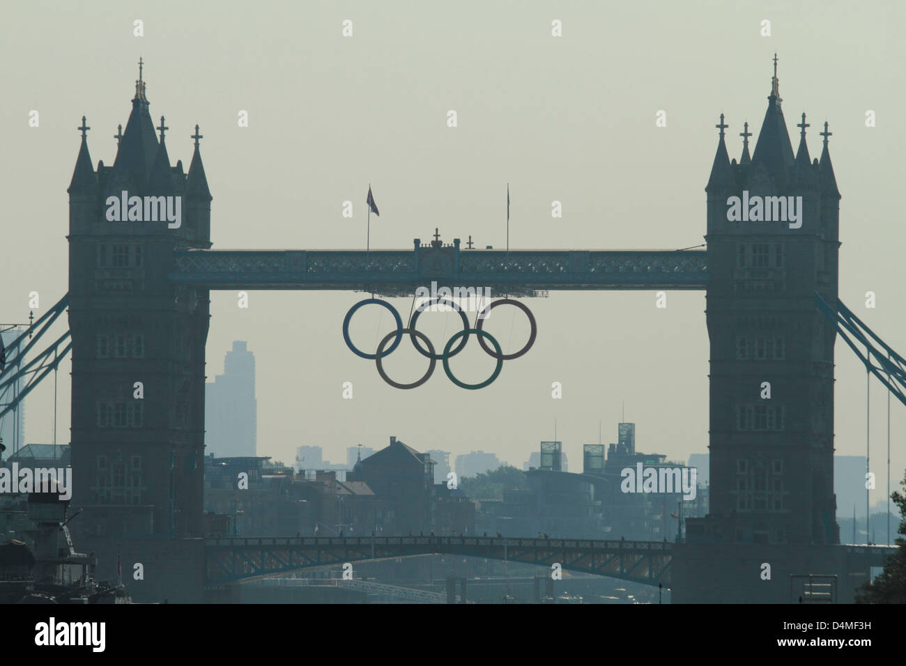 2012 anneaux olympiques se suspendre à la London Tower Bridge sur un ciel voilé misty summers ensoleillé matin. Banque D'Images