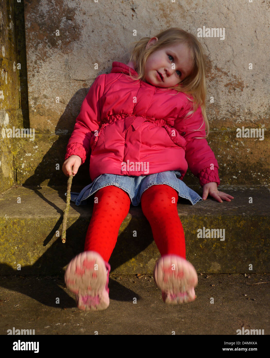 Cute little girl relaxing holding stick Swinging pieds assis sur l'étape Rufford Abbey Country Park le Dukeries Limburg Banque D'Images