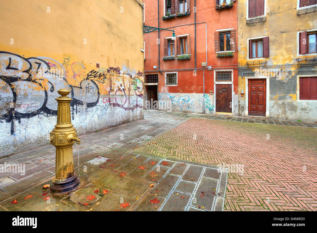 Pompe a eau sur petite place parmi les vieux maisons colorées typiques de Venise et des murs de graffitis à Venise, Italie. Banque D'Images