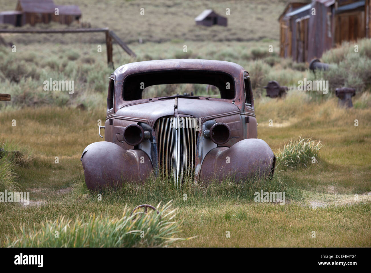 Vieille voiture rouillée entouré de maisons abandonnées dans l'historique ville fantôme de Bodie, en Californie, USA Banque D'Images